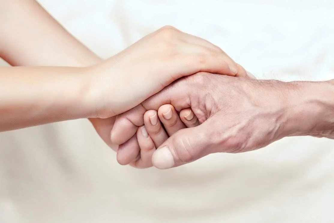 Hands held gently during a hospice care conversation